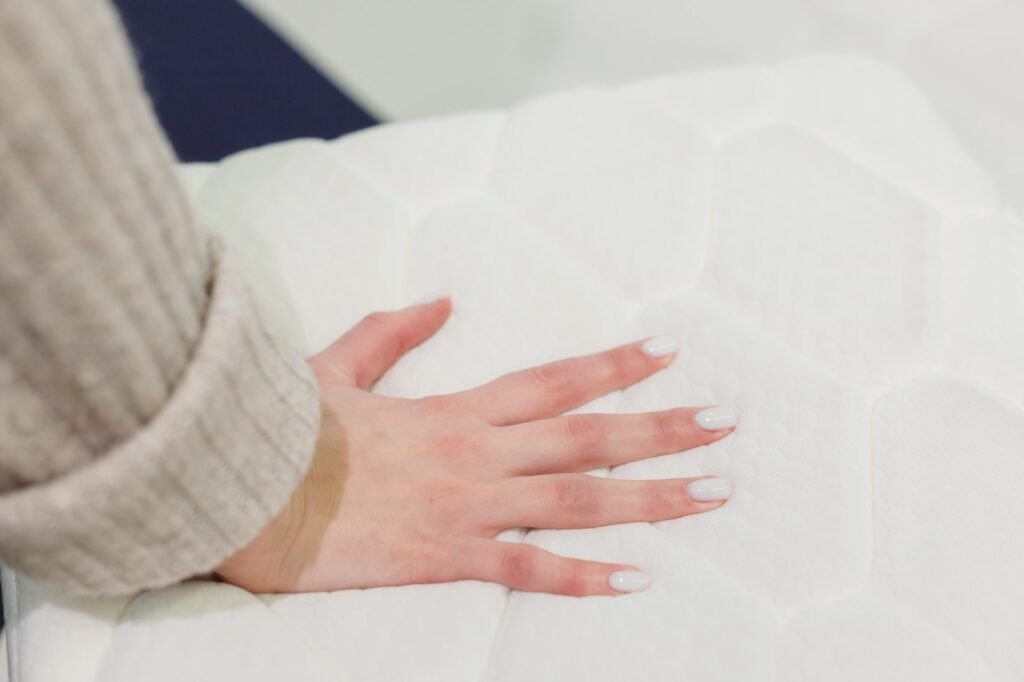 Woman's hand pressing on white mattress. Checking hardness and softness