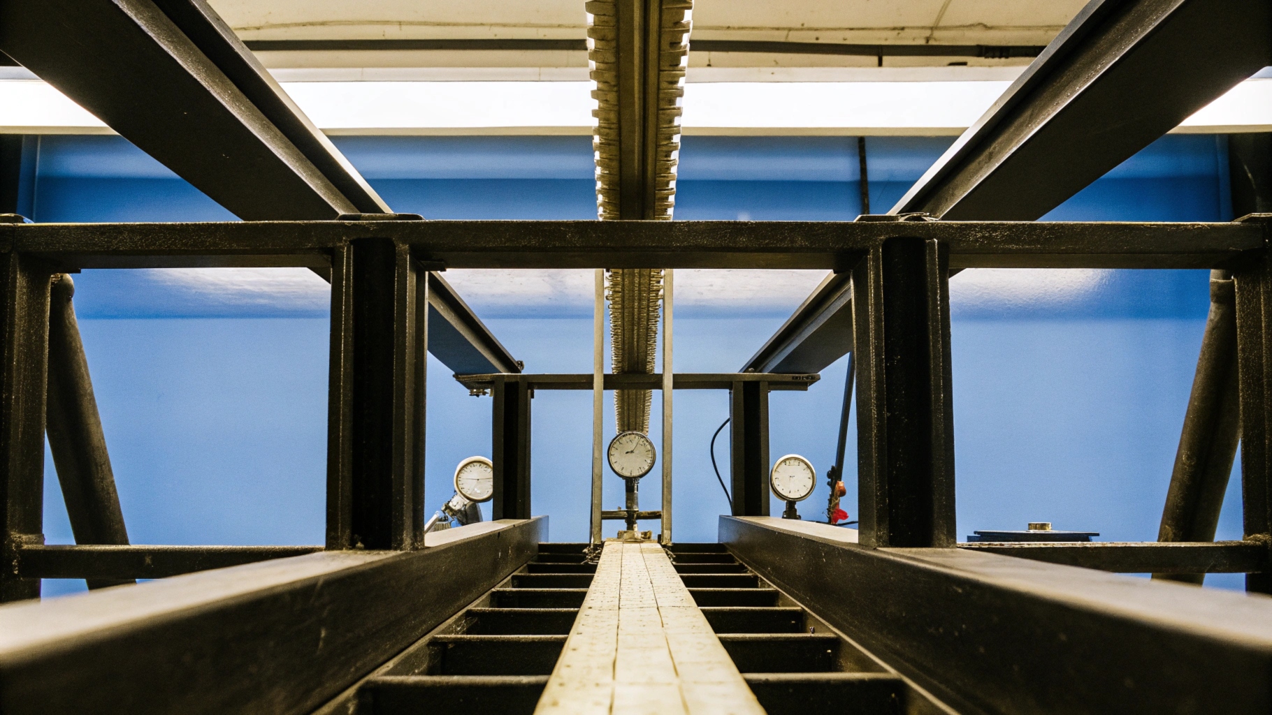 Industrial testing equipment with gauges and metal framework against a blue background.