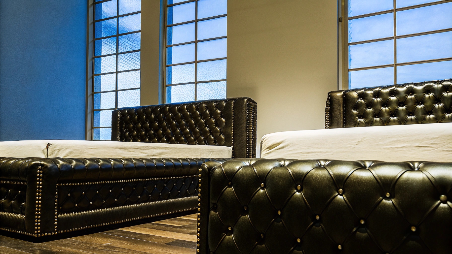 Black tufted leather beds with elegant studded details in a modern bedroom.