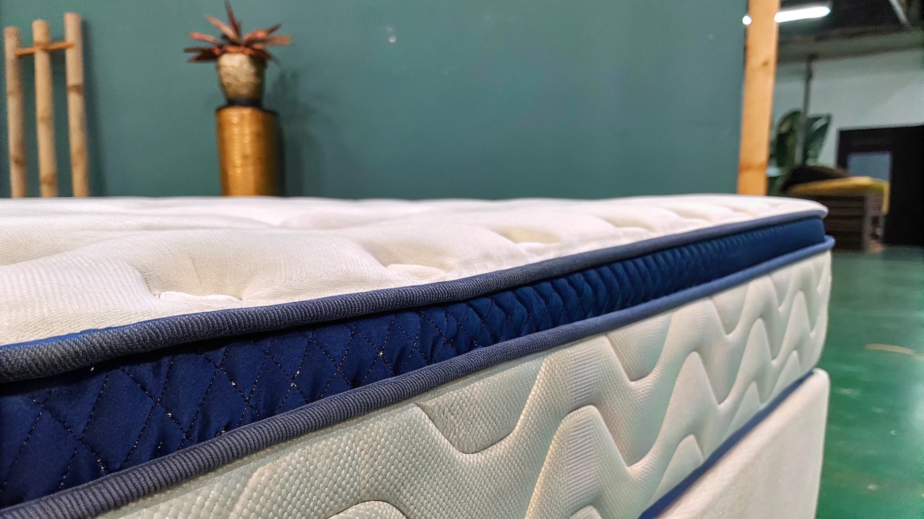 Close-up of a modern mattress with quilted fabric and blue accents in a showroom.