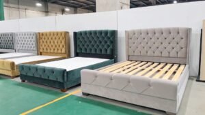 A variety of luxurious tufted bed frames displayed in a showroom, featuring velvet and fabric upholstery in green, gray, and beige tones with wooden slats and elegant headboards.