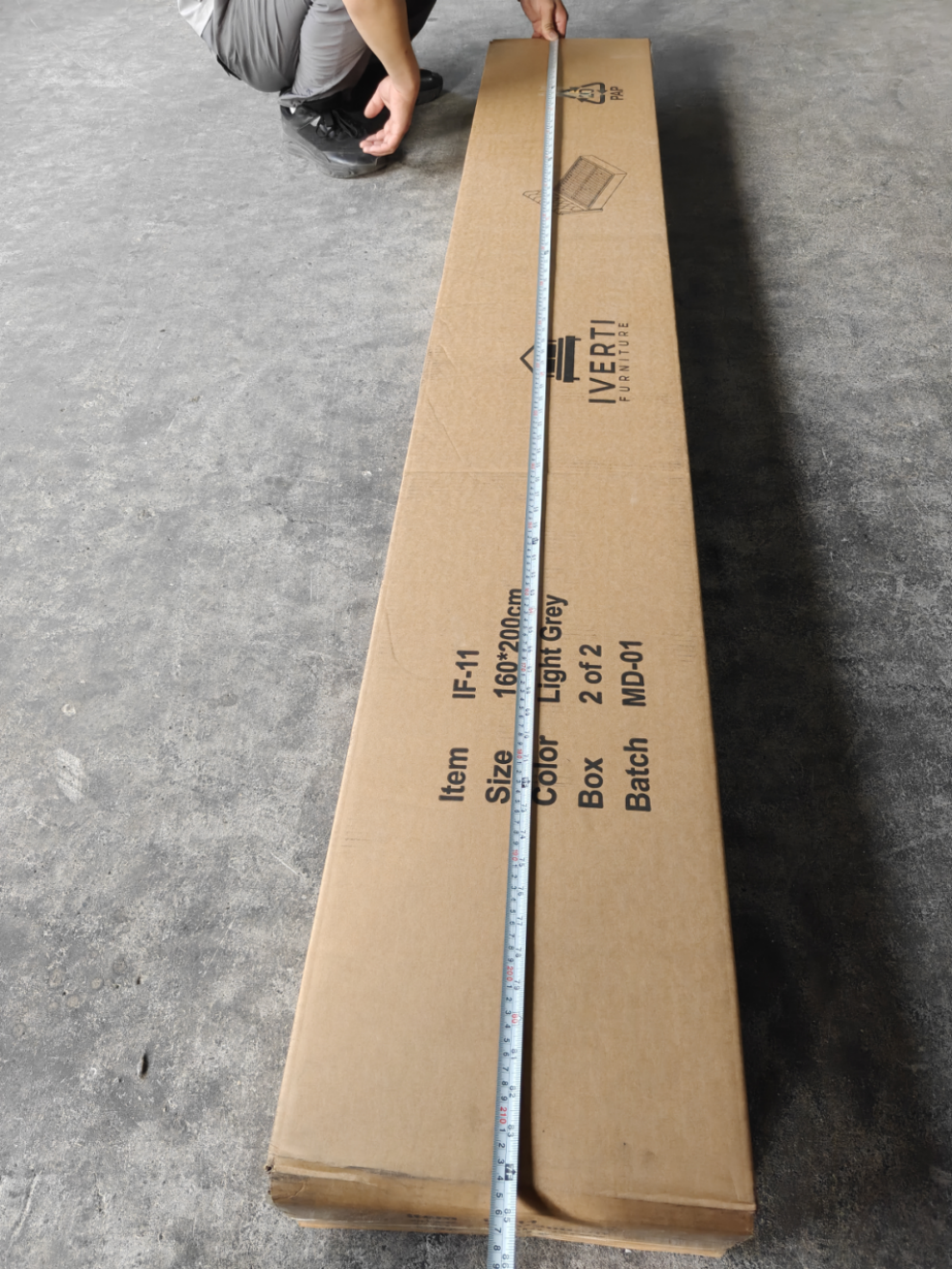 Worker measuring the length of a furniture carton with a tape measure